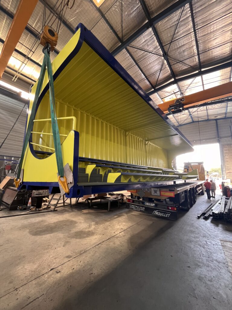 Photo d'un container transformé en tribune par IMTM. Il est en pleine préparation pour la livraison. Monté sur poulie, il va être déposé sur un camion de livraison.